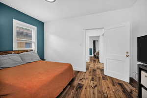 Bedroom with dark wood-style flooring and baseboards