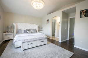 Bedroom with arched walkways, vaulted ceiling, and ensuite bathroom.