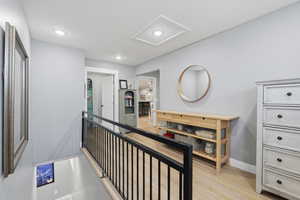 Hall featuring an upstairs landing, light wood-style flooring, and recessed lighting