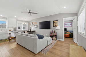 ADU living room featuring lofted ceiling, healthy amount of natural light, hanging lights, ceiling fan, and light wood finished floors