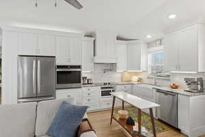 ADU Kitchen with stainless steel appliances, farmhouse sink,  white cabinets, Granite counters, light wood finished floors, and recessed lighting