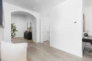 Hall featuring arched walkways and light wood-style floors