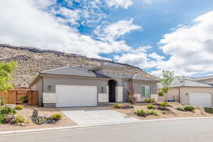 View of front of home with stone siding, a gate, an attached garage, stucco siding, and concrete driveway