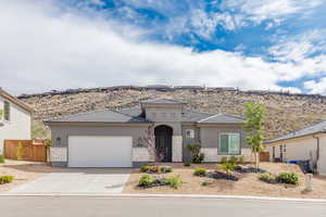 View of front of home featuring stone siding, an attached garage, concrete driveway, stucco siding, and a tiled roof