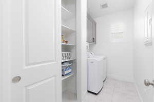 Laundry room with washer and clothes dryer, cabinet space, and light tile patterned floors