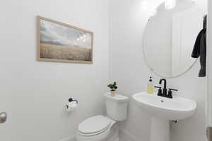 Half bath featuring toilet and baseboards