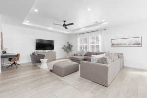 Living area with a desk, light wood-style floors, a ceiling fan, a raised ceiling, and recessed lighting