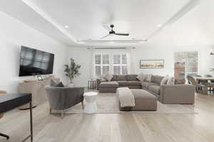Living area with ceiling fan, light wood-type flooring, healthy amount of natural light, a tray ceiling, and recessed lighting