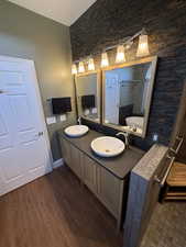 Full bath featuring double vanity, a textured ceiling, dark wood finished floors, and a tub to relax in