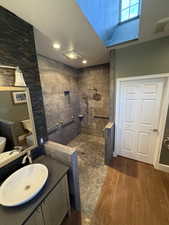 Bathroom with a walk in shower, vanity, and dark wood-style floors