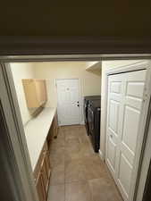 Laundry area with independent washer and dryer and light tile patterned floors