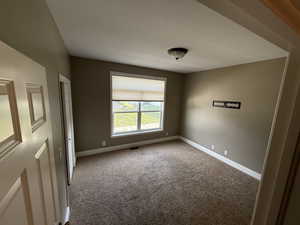 Carpeted spare room featuring baseboards