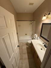 Bathroom with vanity, washtub / shower combination, and light tile patterned floors