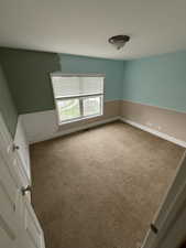 Carpeted spare room featuring baseboards