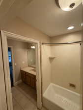 Full bathroom with vanity, light tile patterned flooring, a textured ceiling, and tub / shower combination