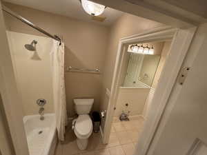 Bathroom with light tile patterned floors and shower / bath combination with curtain