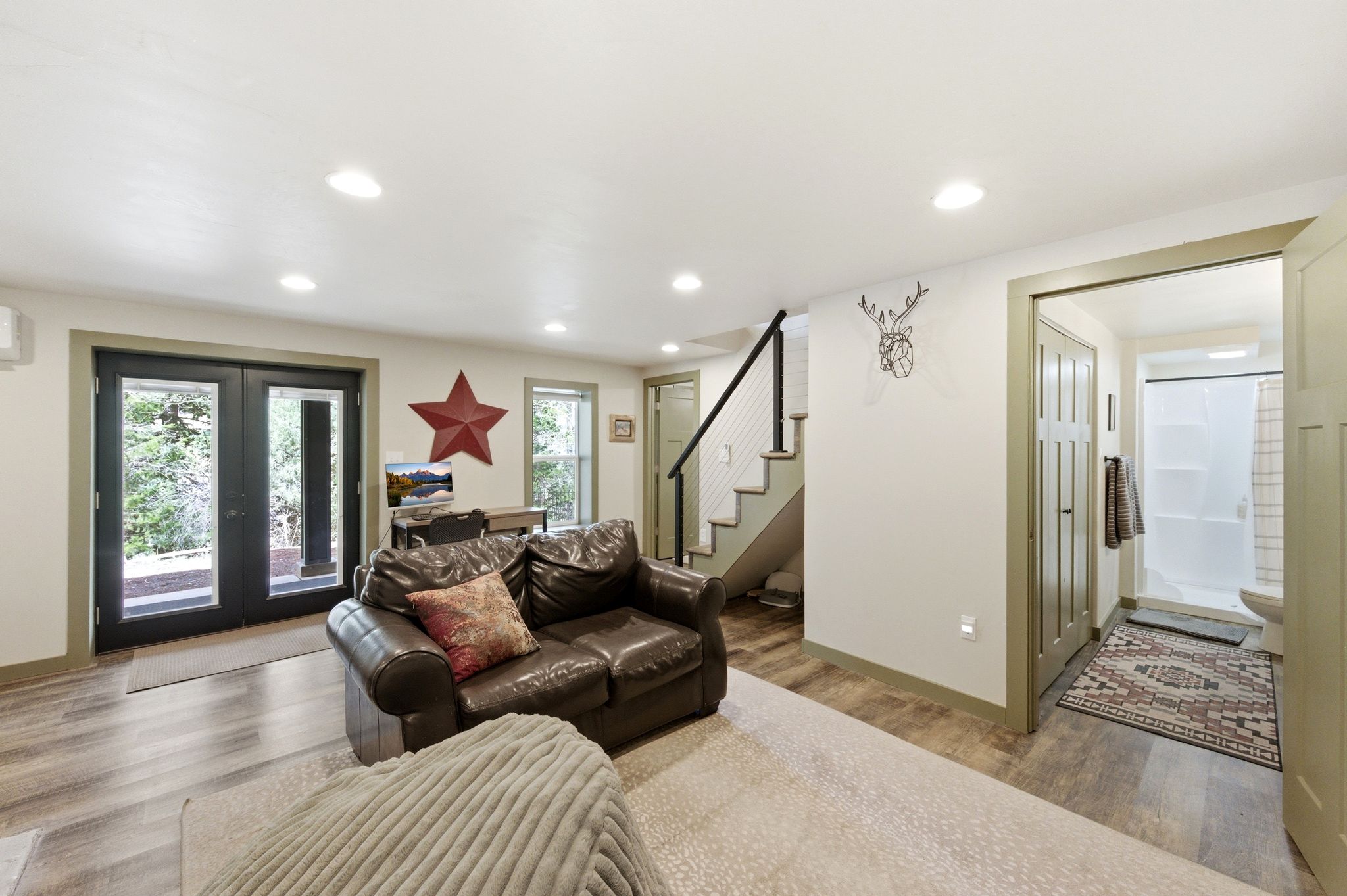 Downstairs living room with french doors, LVP floors, sleeping nook, wood or coal burning stove and recessed lighting