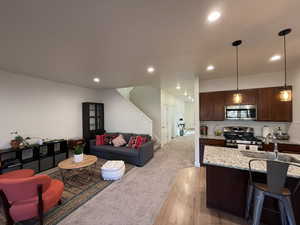 Living room with recessed lighting, light wood-type flooring, and light carpet