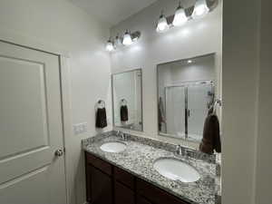 Bathroom featuring double vanity and a shower with shower door