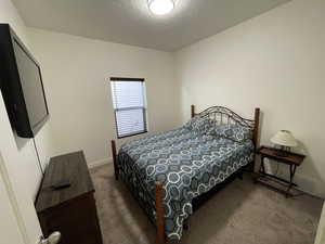 Bedroom with dark carpet and a textured ceiling