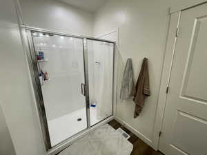 Full bath with a stall shower and dark wood finished floors