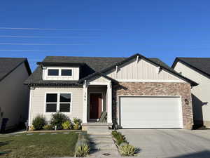 View of front of house featuring a garage, board and batten siding, driveway, roof with shingles, and a front lawn