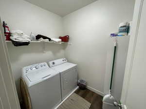 Laundry room with dark wood finished floors and washing machine and dryer