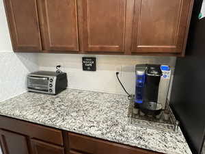 Kitchen view of light stone countertops, decorative backsplash, wood finish cabinetry, freestanding refrigerator, and dark wood finish cabinets