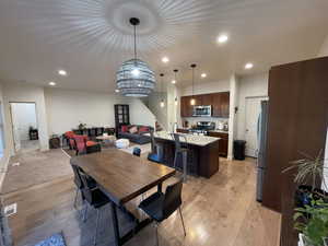 Dining room with light wood-style floors and suspended lighting