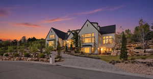 View of front of house featuring stucco siding, a chimney, and a balcony