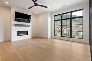 Unfurnished living room featuring ceiling fan, light wood-style flooring, a fireplace, and recessed lighting