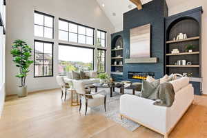 Living area with a large fireplace, light wood finished floors, built in features, recessed lighting, and vaulted ceiling