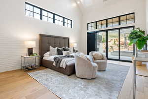 Bedroom with access to exterior, a high ceiling, and light wood-type flooring