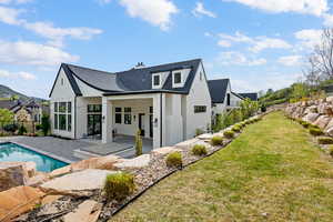 Back of property with a patio, brick siding, a shingled roof, and a chimney