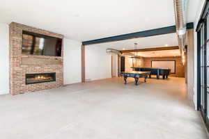 Game room featuring concrete flooring, a fireplace, and beamed ceiling