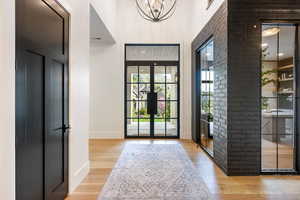 Foyer featuring light wood-style floors, a high ceiling, french doors, and a chandelier