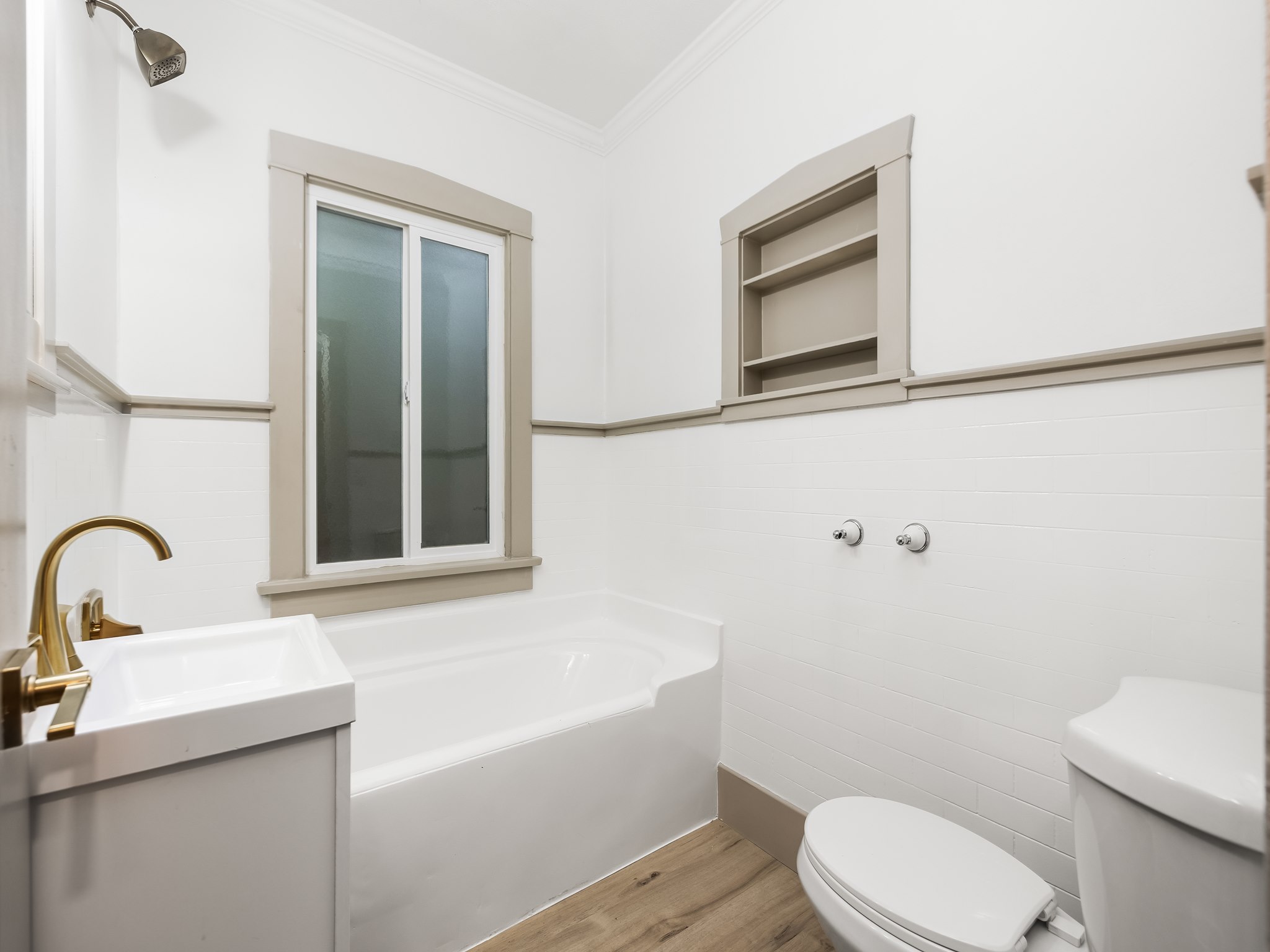 Full bath with ornamental molding, light wood-style flooring, vanity, and a garden tub