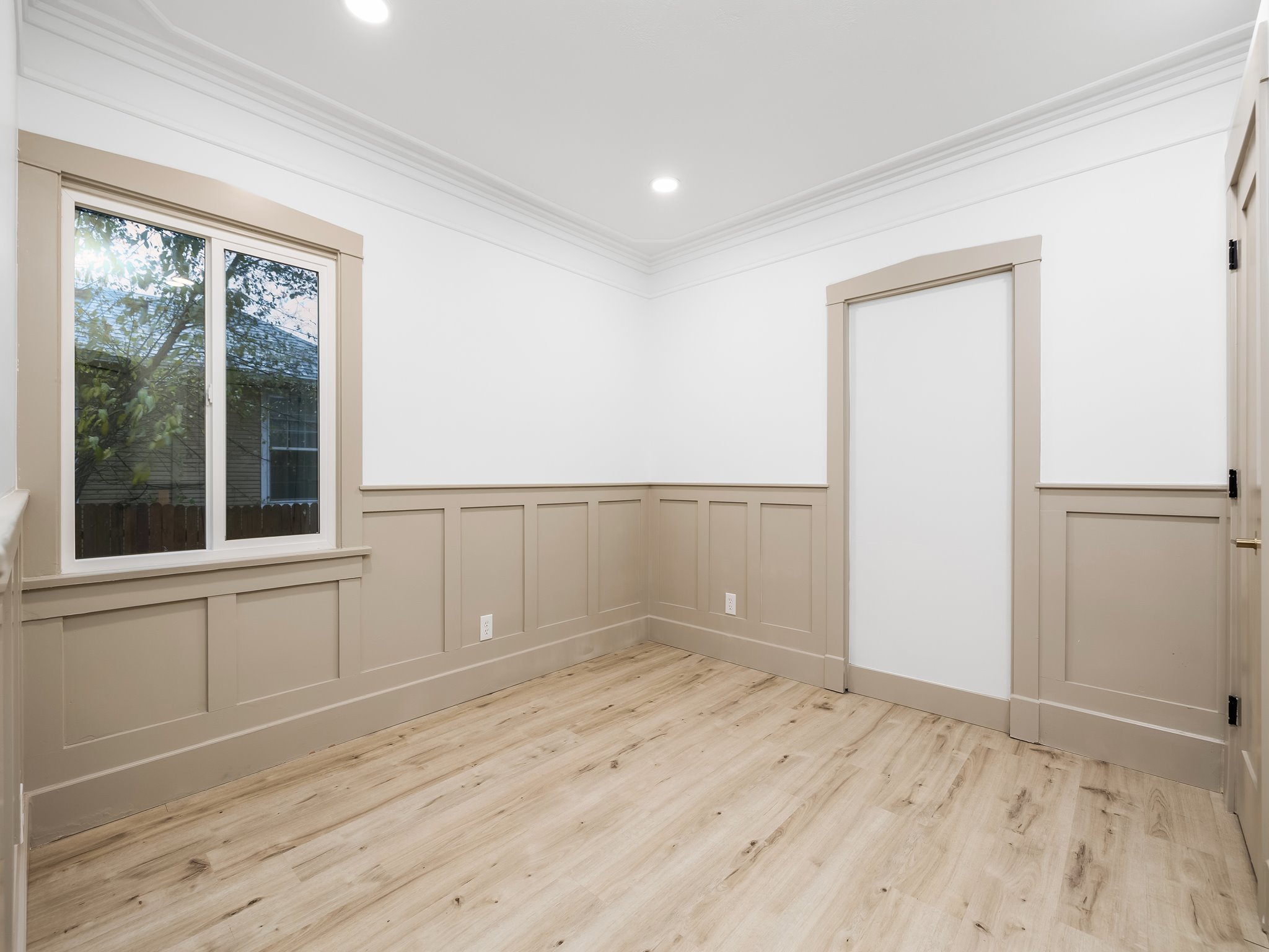 Spare room with light wood-style flooring, a decorative wall, crown molding, a wainscoted wall, and recessed lighting
