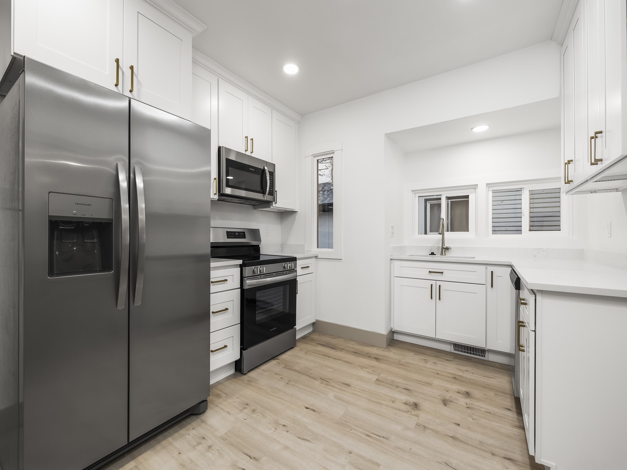 Kitchen with stainless steel appliances, white cabinets, light wood finished floors, light stone counters, and recessed lighting