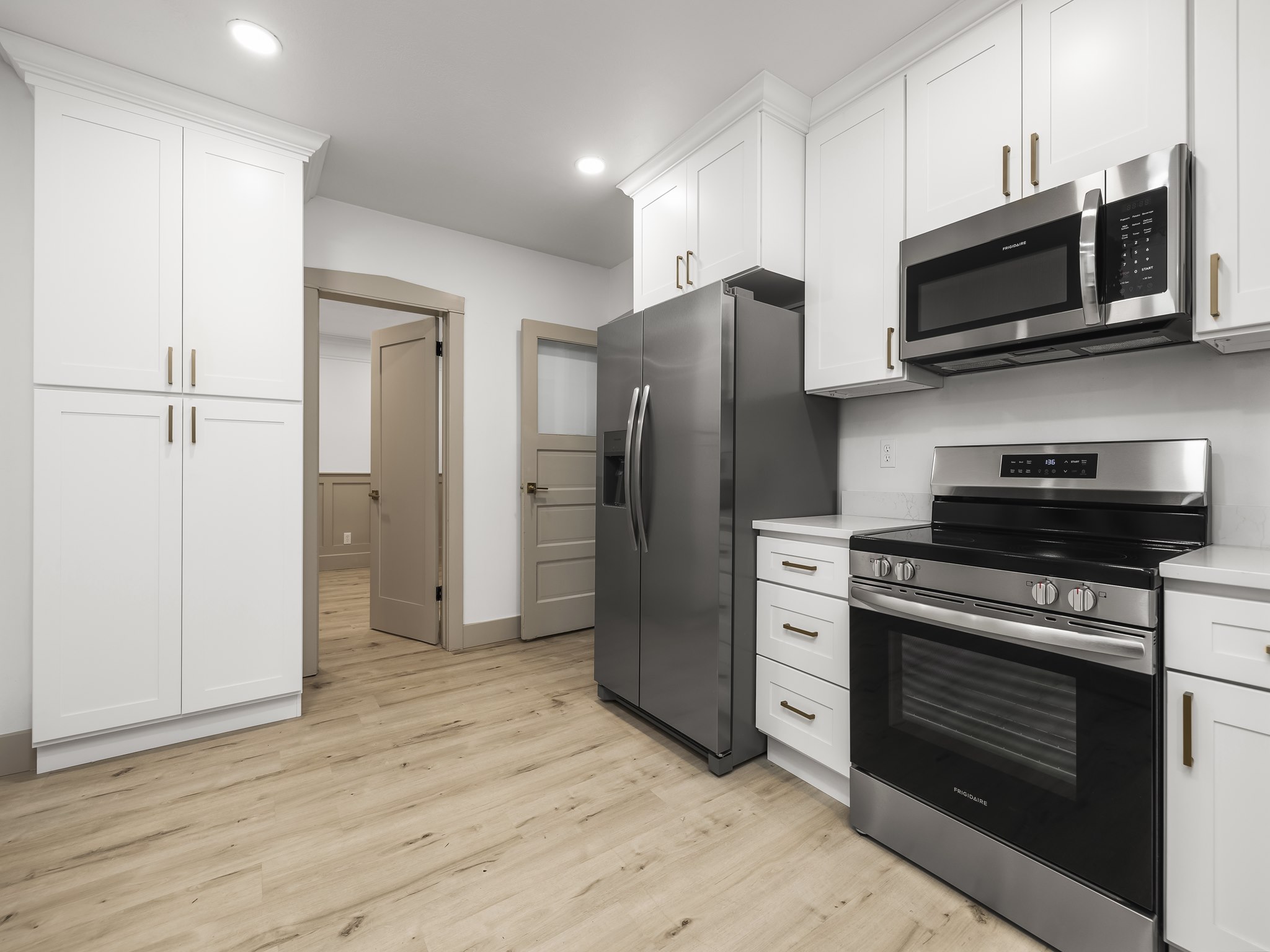 Kitchen featuring stainless steel appliances, white cabinets, light wood finished floors, and recessed lighting