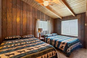 Carpeted bedroom with vaulted ceiling with beams, wood walls, and wooden ceiling