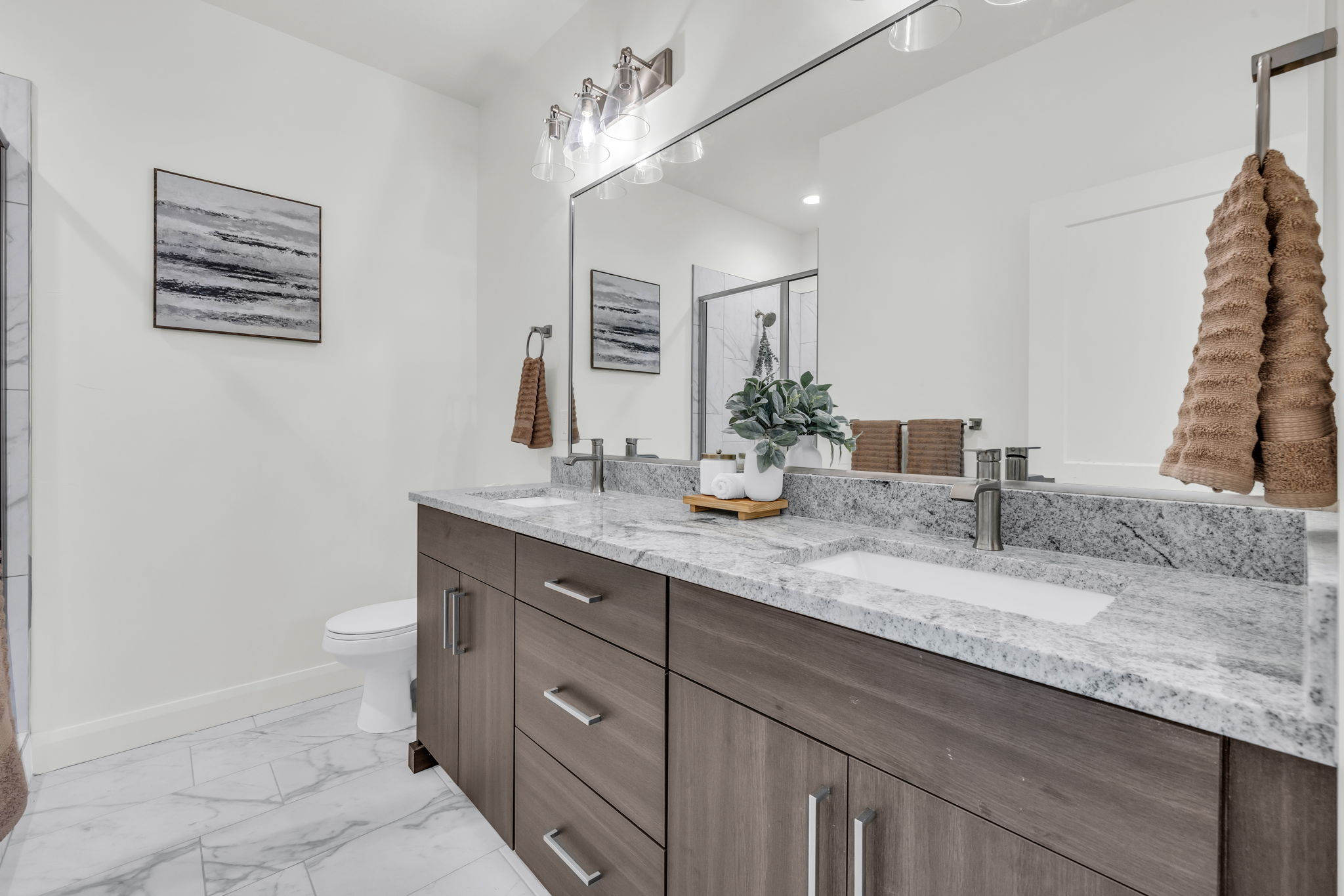 Bathroom featuring double vanity, a marble finish shower, and light marble finish floors