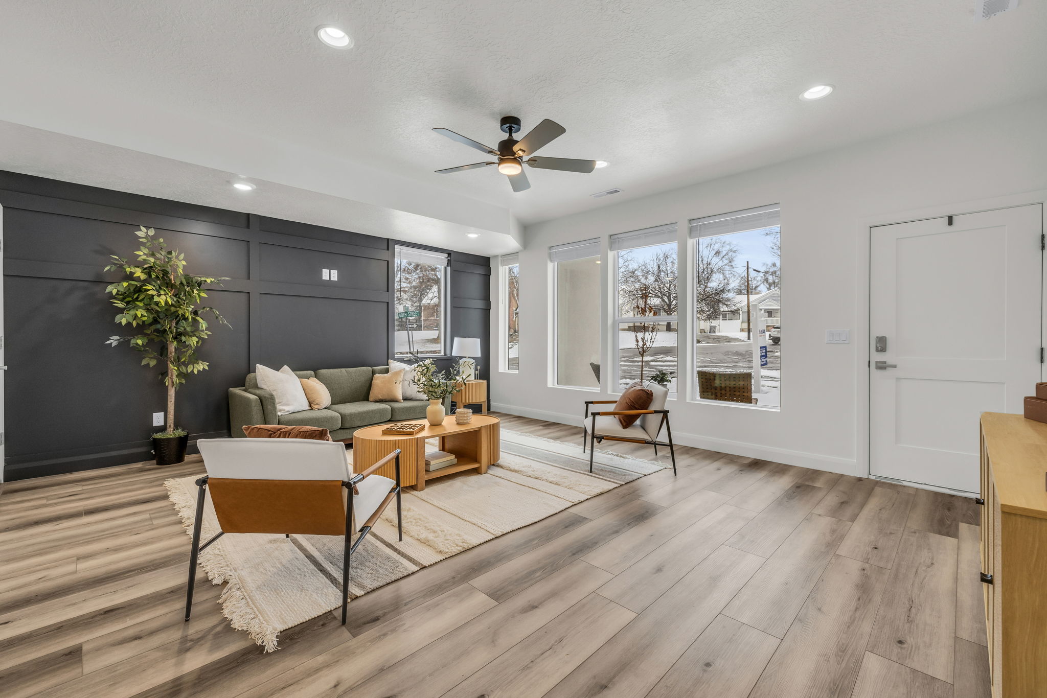 Living room with ceiling fan, recessed lighting, light wood-type flooring, and a decorative wall