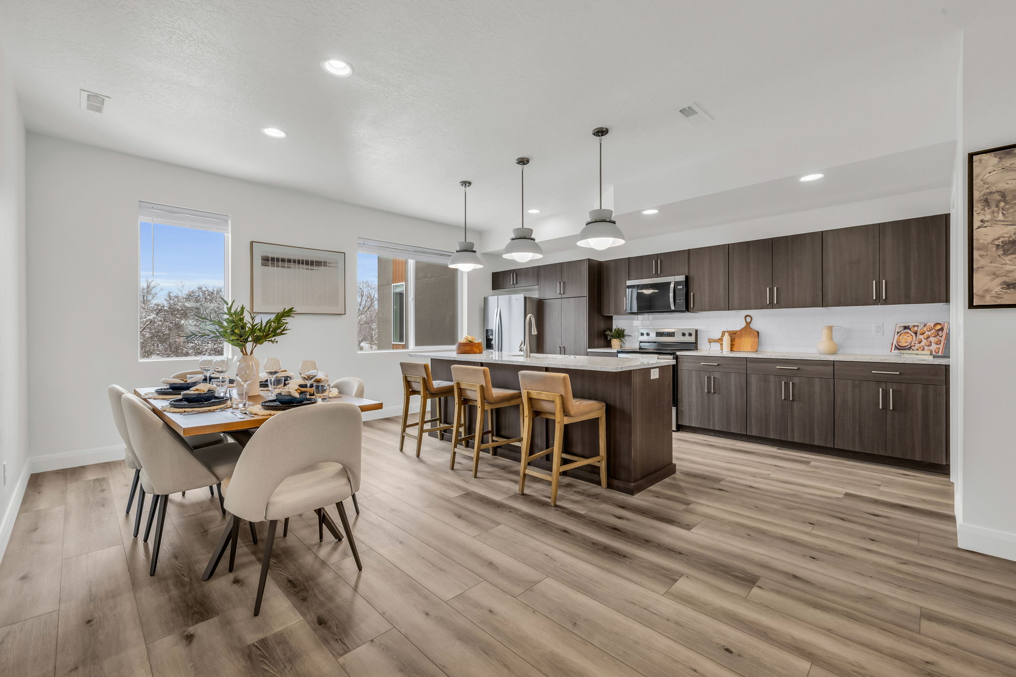 Kitchen featuring a kitchen island with sink, dark wood finish cabinets, a kitchen bar, pendant lighting, and stainless steel appliances