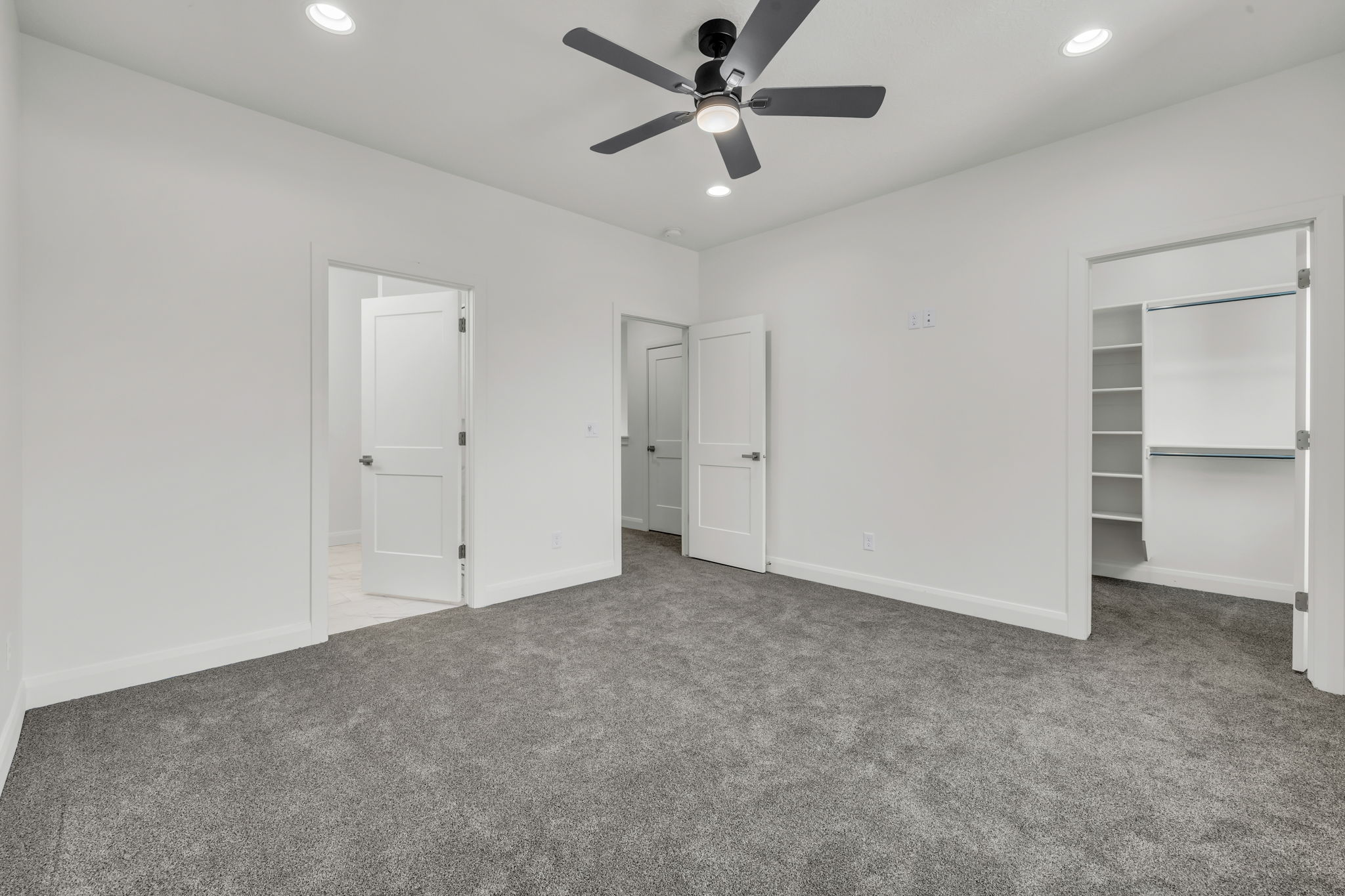 Unfurnished bedroom with a walk in closet, carpet, recessed lighting, and ceiling fan