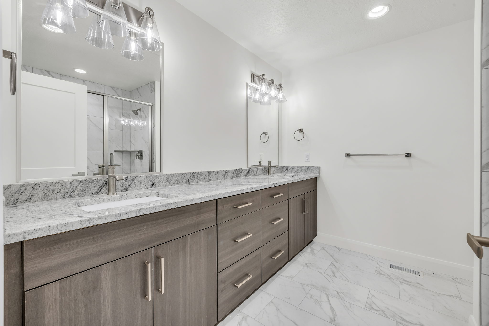 Bathroom with double vanity, light marble finish floors, recessed lighting, and a marble finish shower