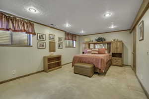 Bedroom with light colored carpet, crown molding, and a textured ceiling
