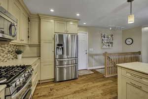 Kitchen featuring stainless steel appliances, light wood-style floors, light stone counters, cream cabinets, and rail lighting