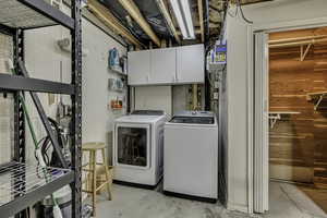Laundry room with cabinet space, concrete floors, washing machine and dryer, and wood walls