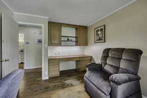 Office with built in study area, dark wood finished floors, and crown molding